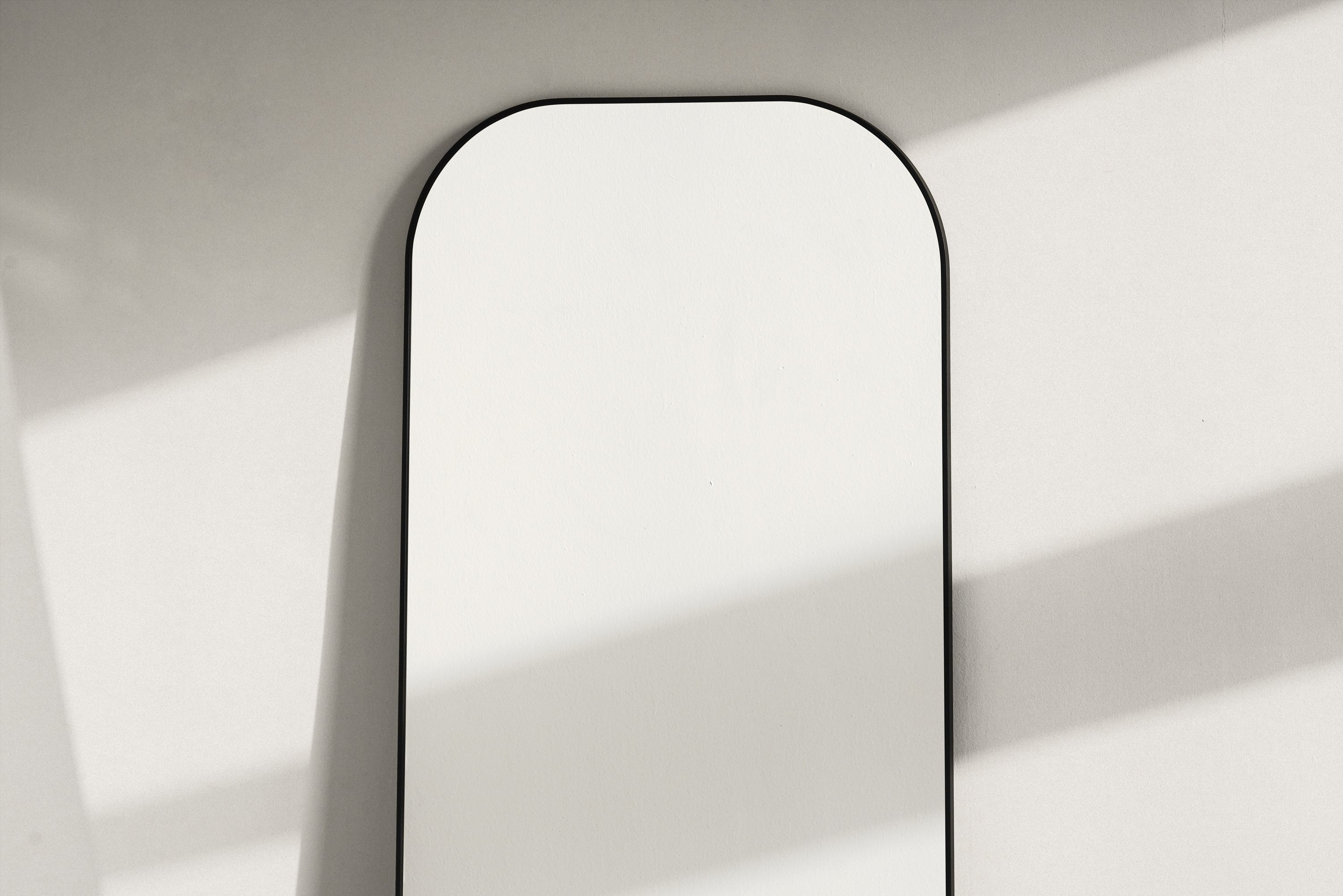 Upper section of the Elliot black curved full-length mirror in soft natural light